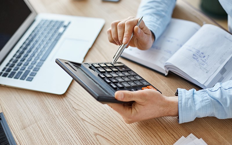 man-doing-calculations-on-a-calculator-at-his-desk